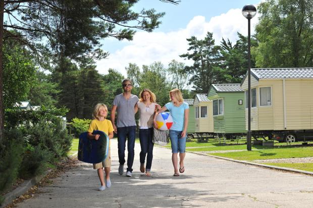 a family walks down a sidewalk in front of mobile homes