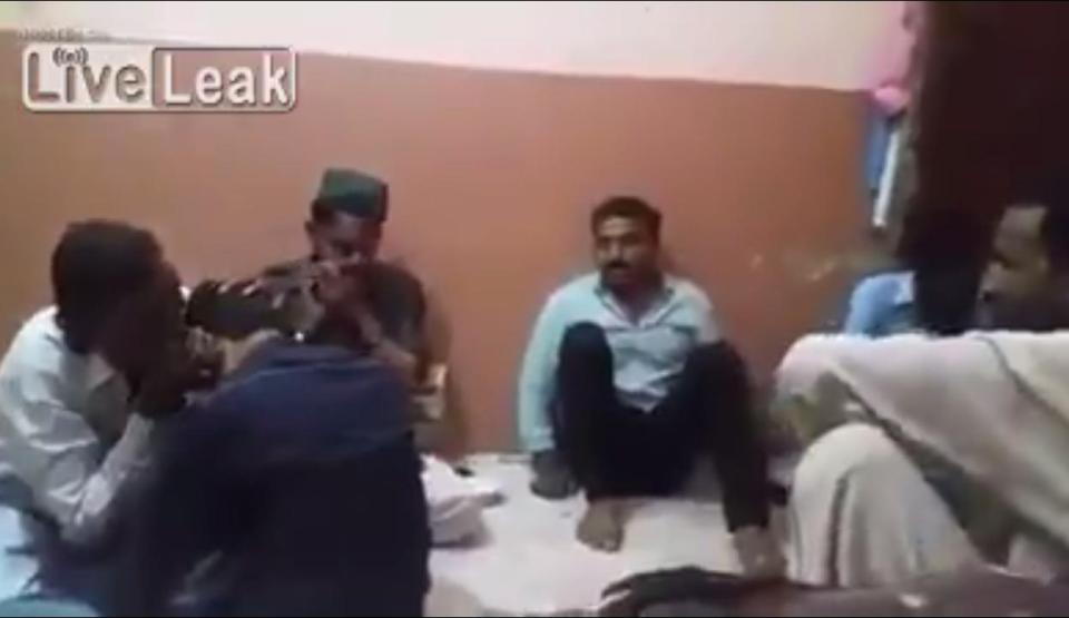  The man in the green shirt sits quietly watching as a religious leader, far left, performs a ritual to drive evil spirits from a young man in Pakistan