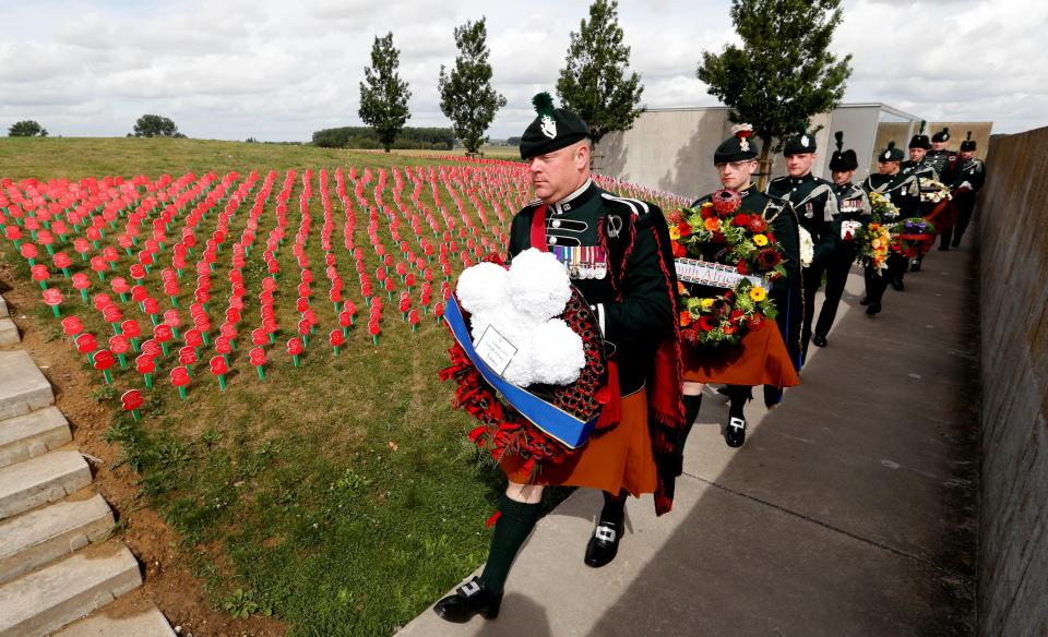  Soldiers march past a field of memorial poppies at Tyne Cot