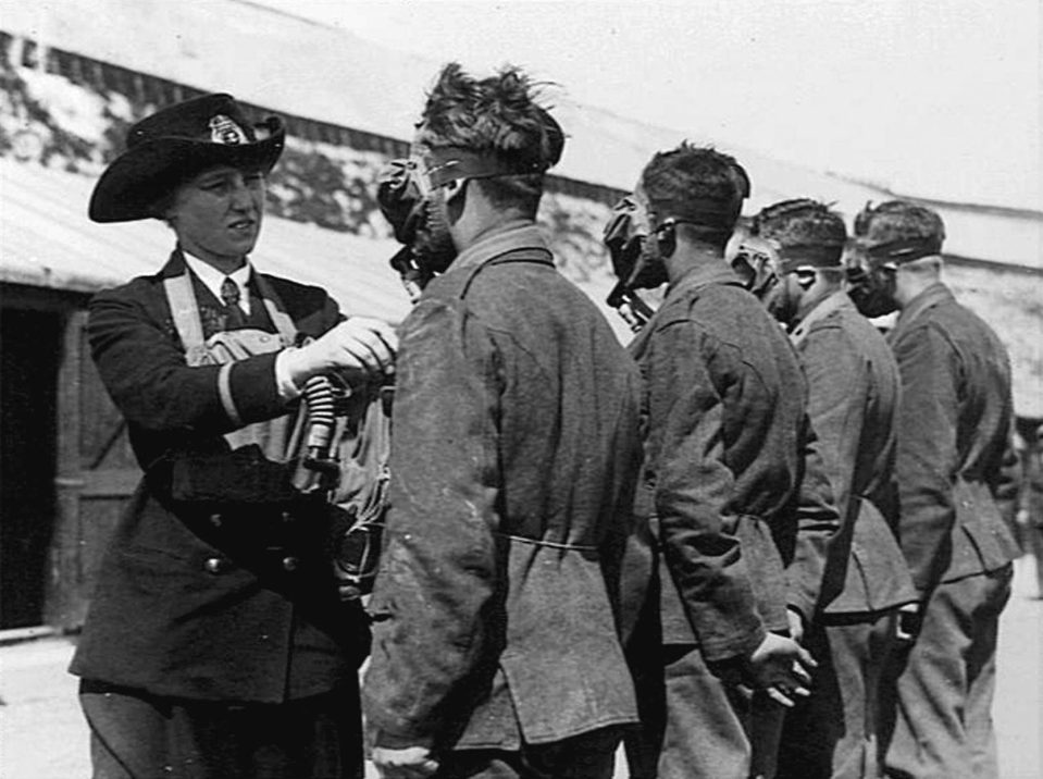  A member of the Women's Royal Naval Service in 1918 instructs new male recruits on how to put on a gas mask.