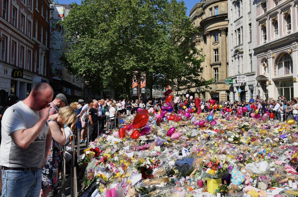  Mancunians mourn at the site of floral tributes for the 22 who lost their lives