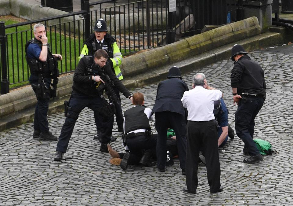  A policeman points a gun at terrorist Khalid Masood as emergency services attend the scene outside the Palace of Westminster