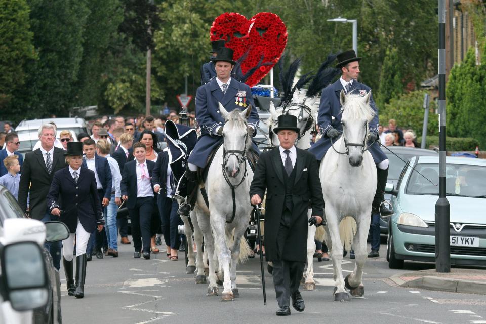  Dozens of mourners walked behind the coffin with a large red heart on the top