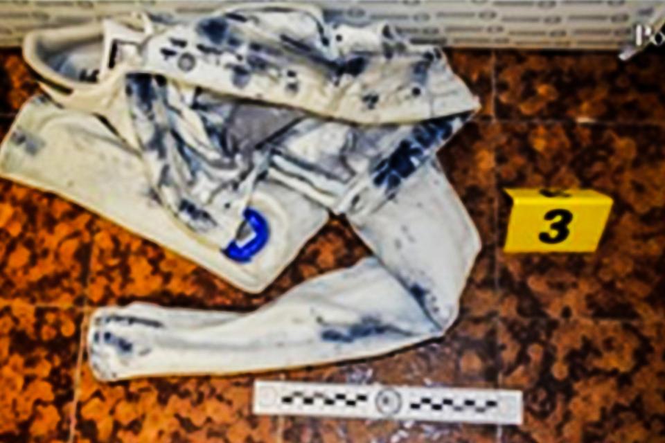  A filthy piece of clothing lies on the ground next to a police evidence number