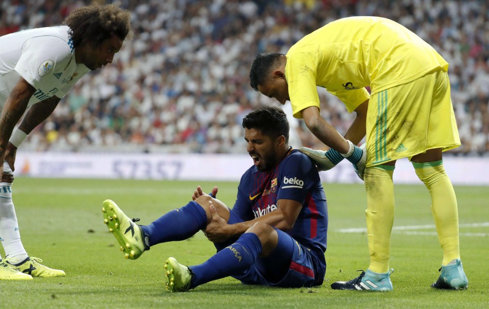 Luis Suarez clutches his right knee in pain during Barcelona’s defeat to Real Madrid