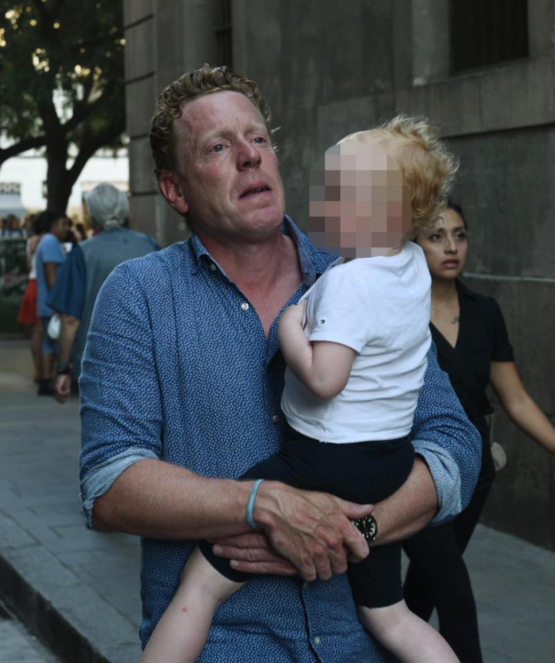  A man pictured carrying a small child following the deadly assault which left more than a dozen dead