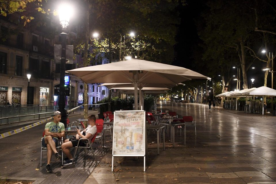  Two young men talk to each other in an empty terrace in Las Ramblas after the area was partially reopened by authorities