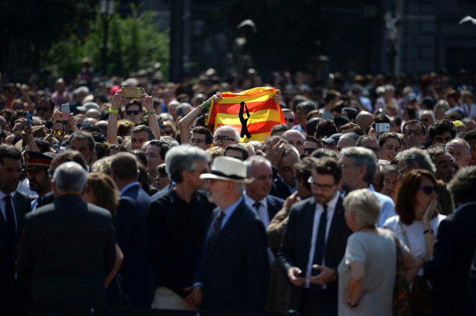 A Catalonian flag is raised above the crowd in Barcelona today