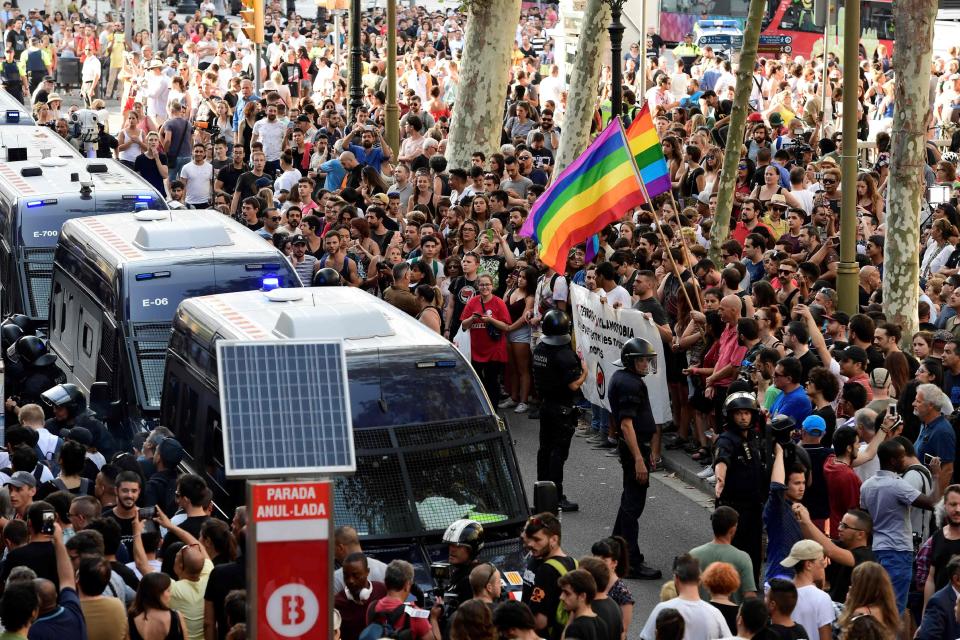  Police officers stand guard as anti-far-right protesters, some of them holding rainbow flags, gather against a demonstration by members of the Spanish right-wing group Falange on Las Ramblas