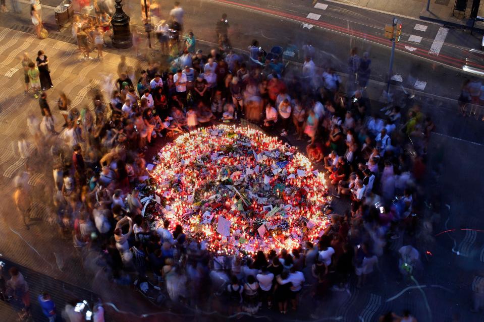  People gather at a memorial tribute of flowers, messages and candles to the victims on Barcelona's historic Las Ramblas