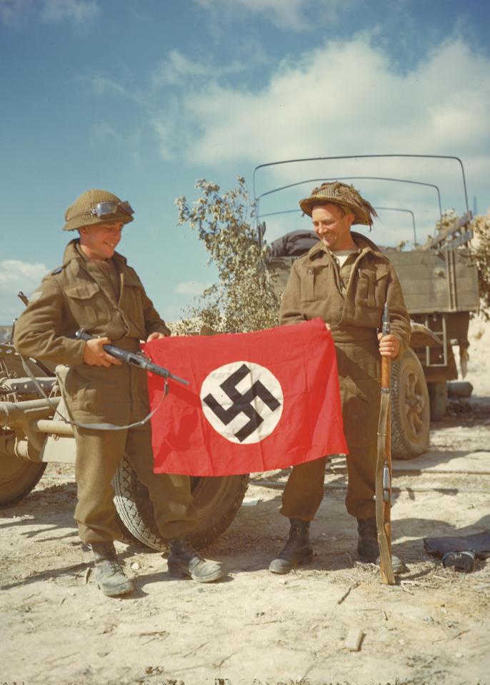  Canadian soldiers pose with a Nazi flag they recovered after German troops fled north