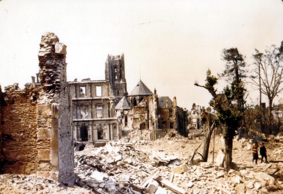  Two locals make their way slowly across rubble from the shattered church of Saint-Lo