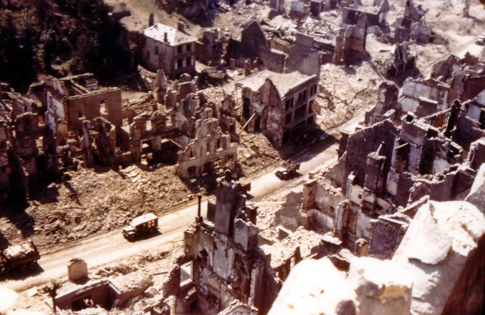  An ambulance makes its way through the hollowed out buildings of Saint-Lo followed by a jeep