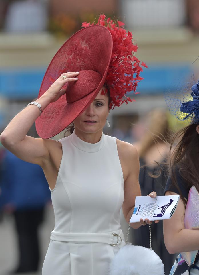  A woman in a cream sleeveless dress was seen propping her hat up as the wind picked up