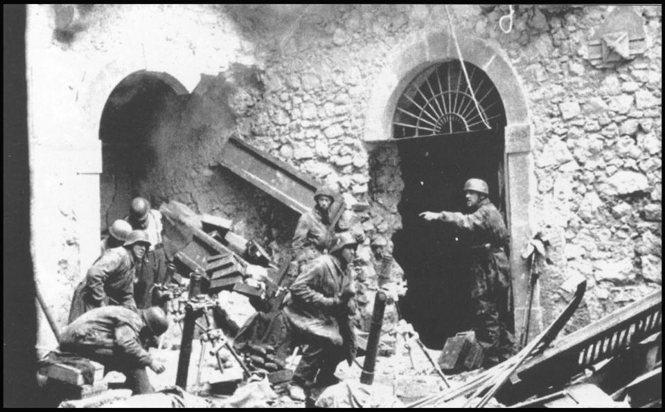  Among the ruins of the Monte Cassino abbey, a paratrooper gives instructions to a mortar team