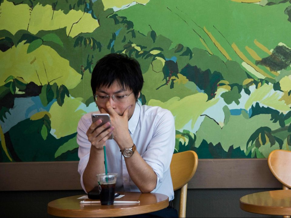  A man checks his smartphone as he sits in a cafe at Ginza business district in Tokyo after a text message warning was sent to mobile phones