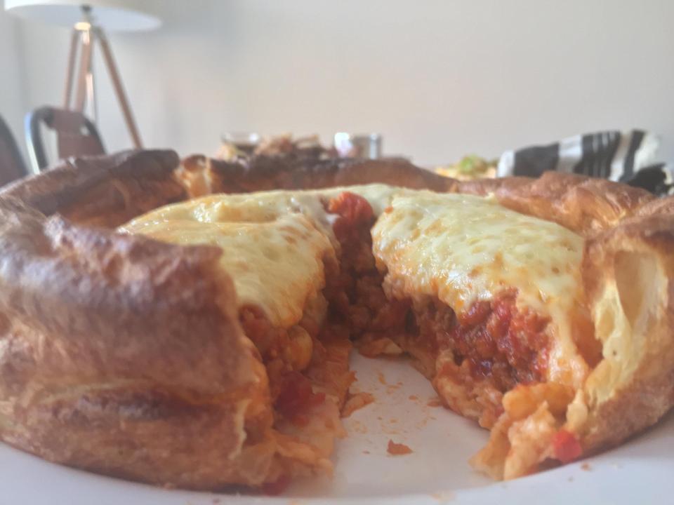  A close up of the pizza shows the thick layer of cheese oozing over the meat ragu below