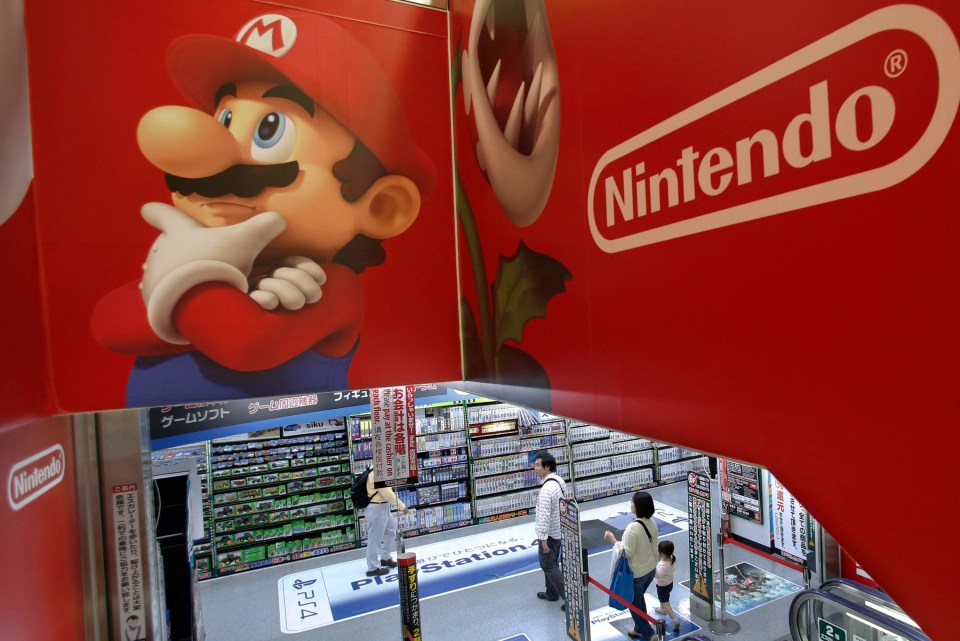 Shoppers walk under the logo of Nintendo and Super Mario characters at an electronics store in Tokyo