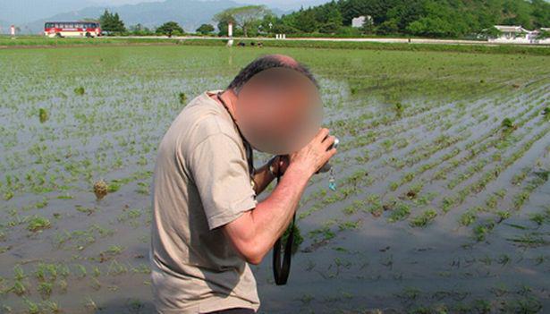  A tourist is shown taking pictures in a field in the crackpot nuclear state