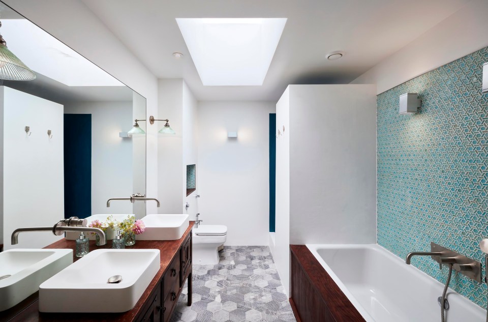 The bathroom has his and hers sinks and the blue tiled wall adds a dash of colour to the neutral palette