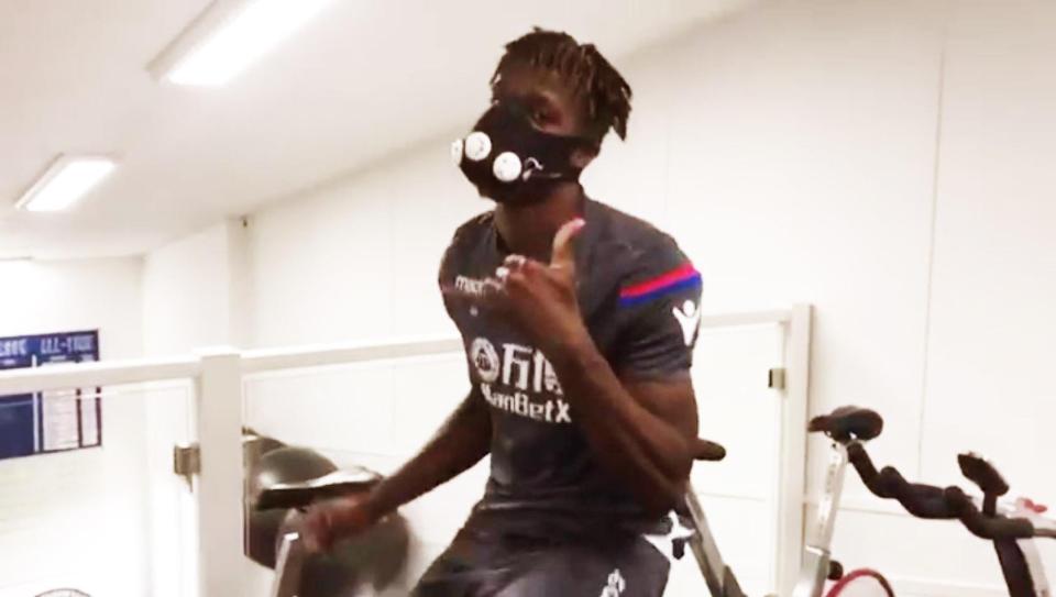  Crystal Palace winger Wilfried Zaha gives fans the thumbs up during his rehab workout on an exercise bike