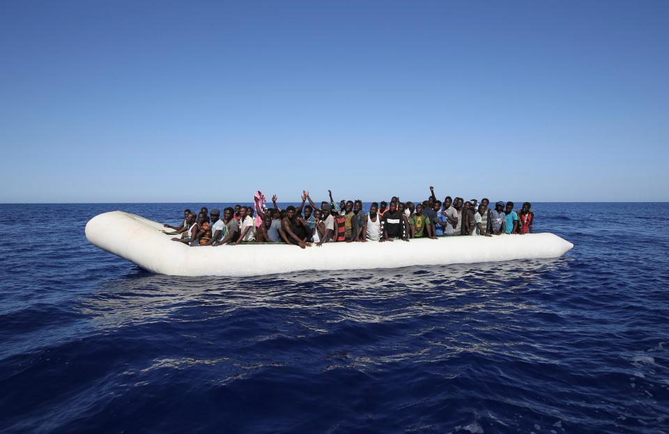  Migrants on a rubber boat gesture before they are rescued off the Libyan coast