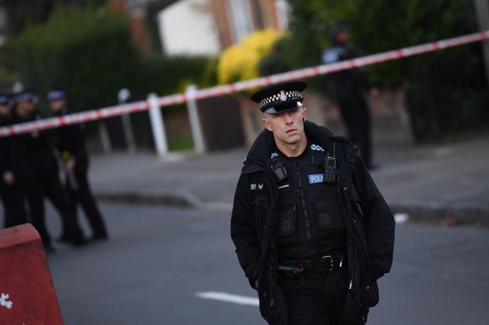  Police stand guard during a police raid in Sunbury, Surrey