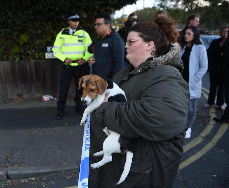  A resident waits with her dog outside the police cordon