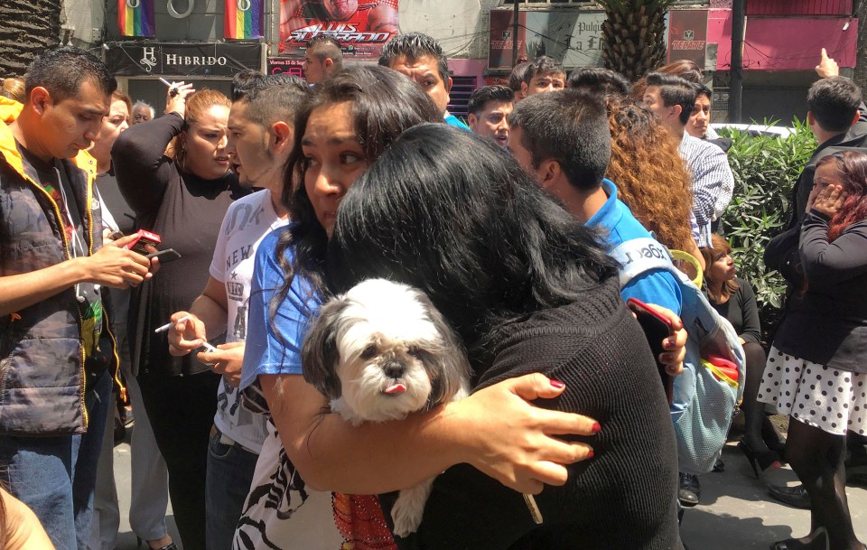 A woman cradles her dog following the devastating tumour that left over 100 dead