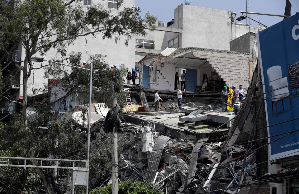 Rescue workers and volunteers search for the injured in the rumble of a collapsed building 