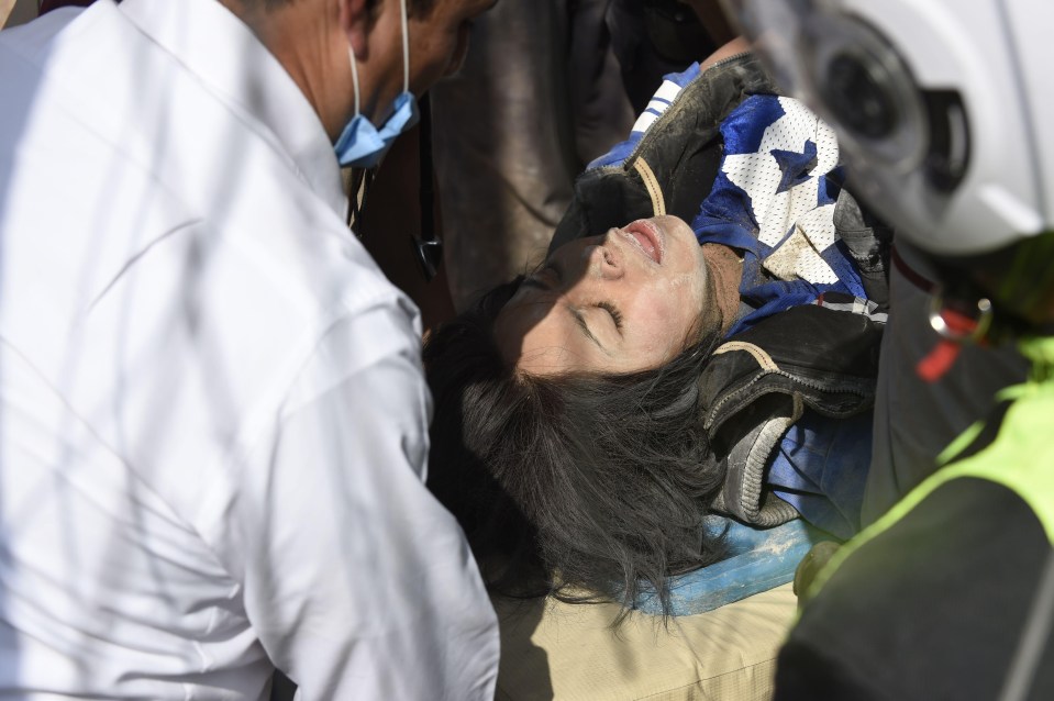 A woman covered in dust is rescued by emergency services following a devastating 7.1 earthquake at the centre of the country