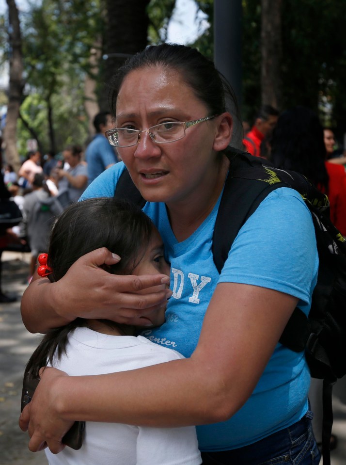 A terrified woman hugs a child tightly outside a school in Mexico City 