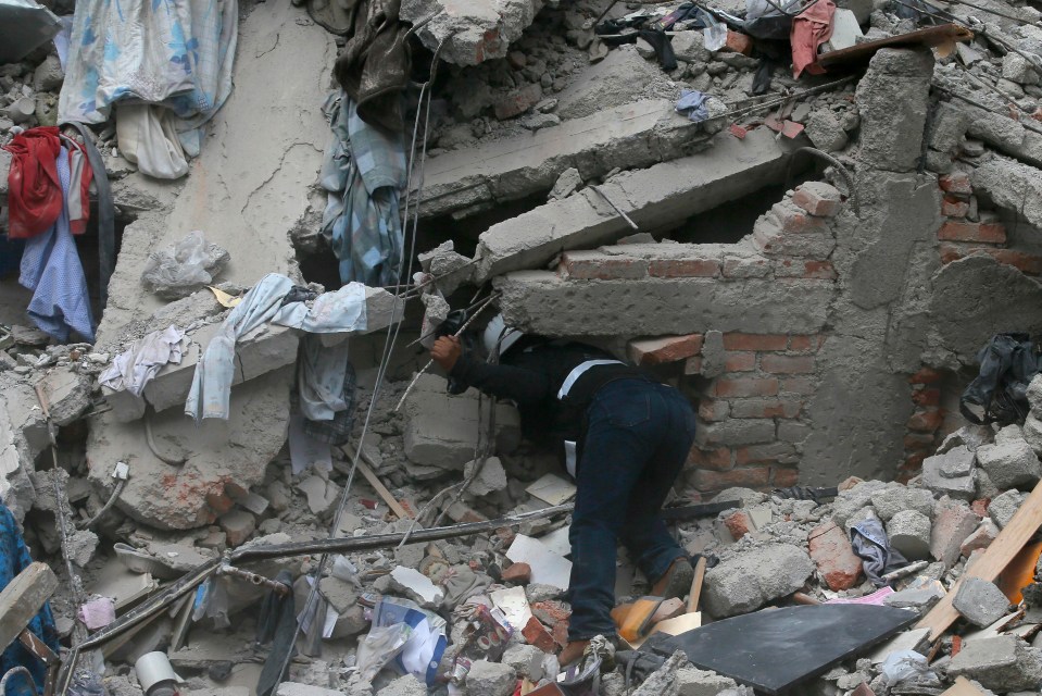 A rescue worker leans in a building flattened by the quake 