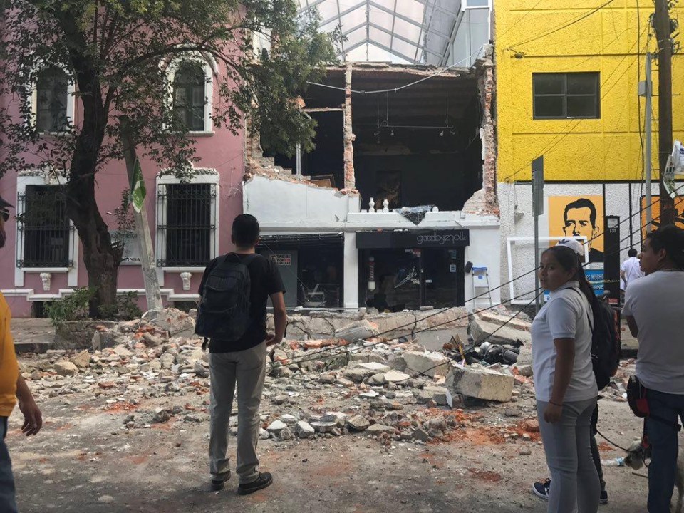 Residents looks on at the large gaping hole in a building 