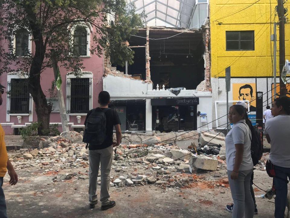  Residents looks on at the large gaping hole in a building