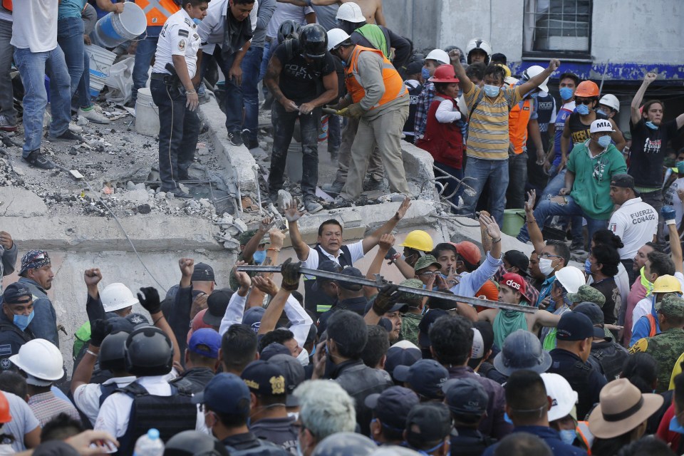 A man tells the crowd to quieten down so rescue workers can hear the those trapped underneath the rubble 