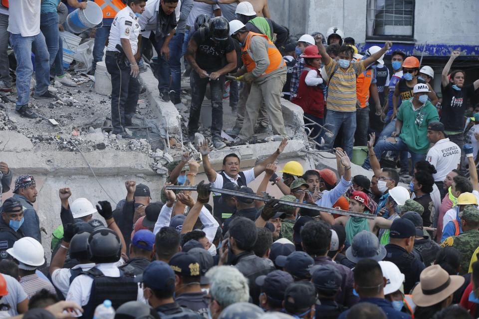  A man tells the crowd to quieten down so rescue workers can hear the those trapped underneath the rubble