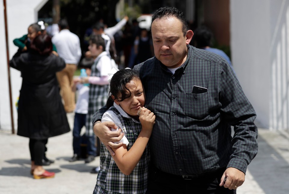 A man comforts a frightened student as he collects her from her school in the Roma neighborhood