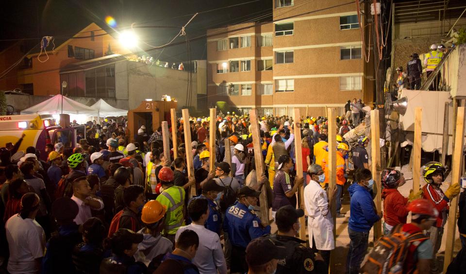  Volunteers carry pieces of wood to help prop up sections of the collapsed school