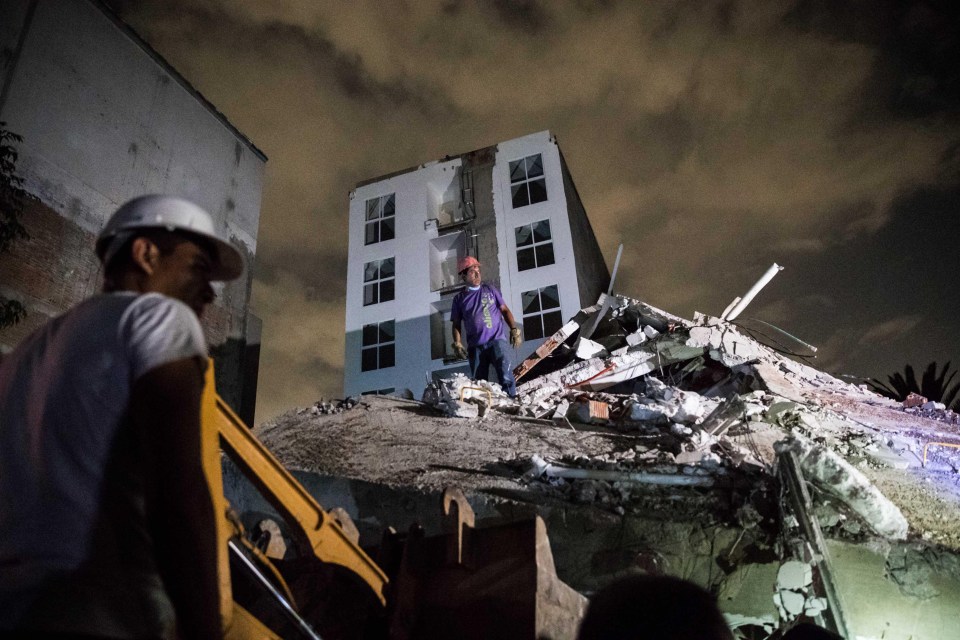 A man stands on a pile of rubble during the overnight searches