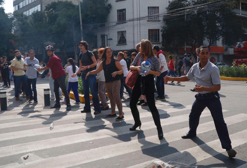 People move bottle of water during rescue efforts on a collapsed building 