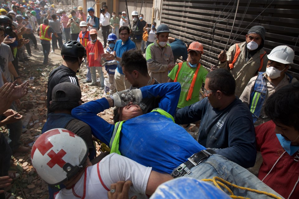 Rescue workers and volunteers move an injured man from the debris 