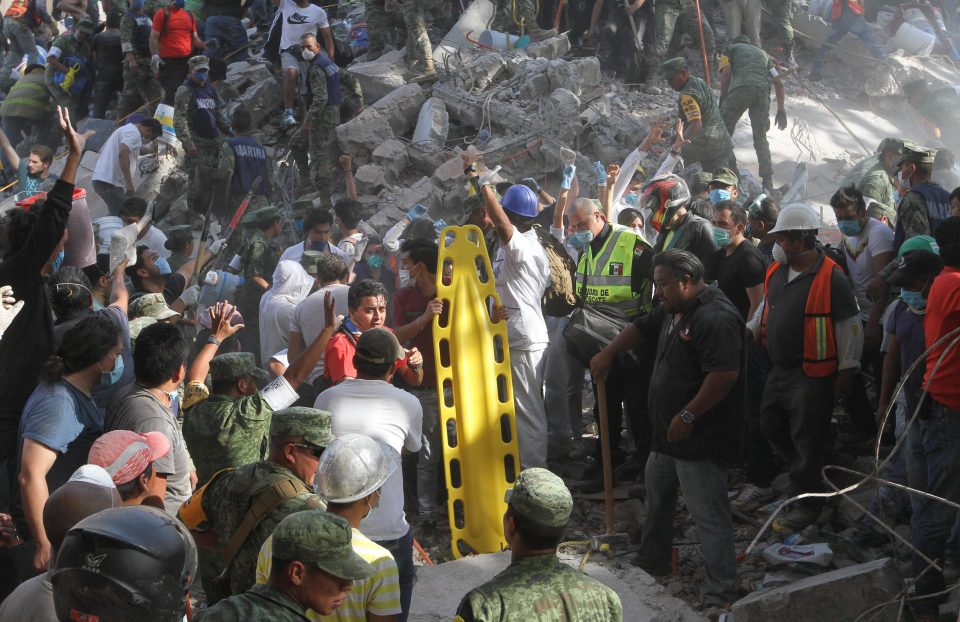  Rescuers go to the aid of a potential survivor buried in the rubble