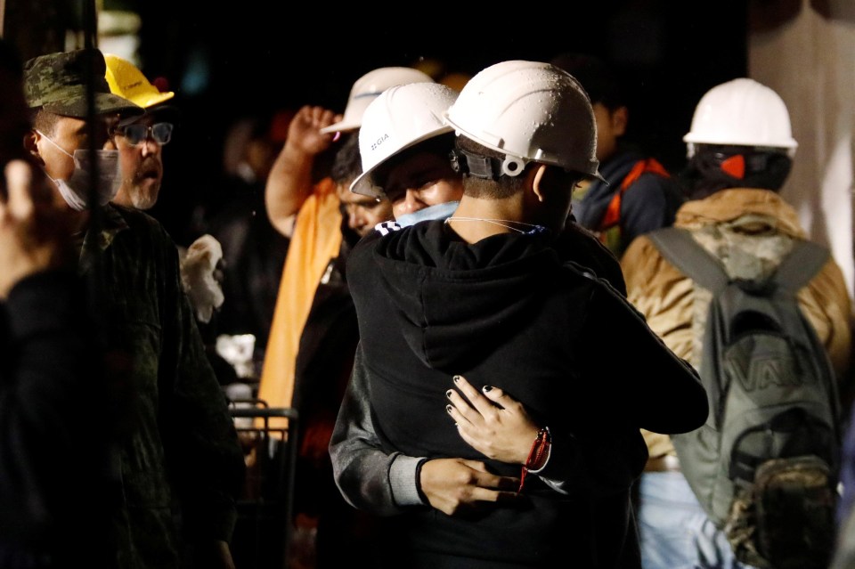 People helping with the rescue efforts embraced as they fought to find people alive in the rubble