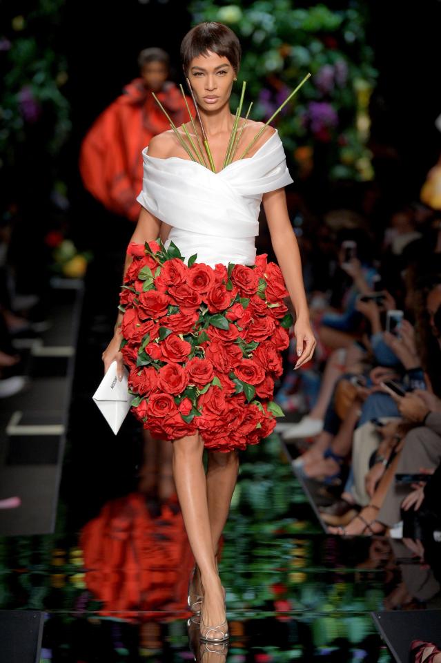  With a skirt adorned with red roses and green stems appearing from her white top