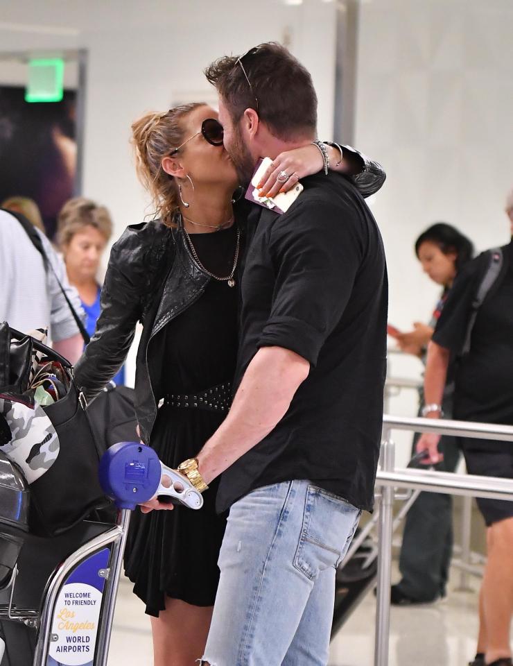  The singer kisses Chad inside the airport as he pushes her trolley