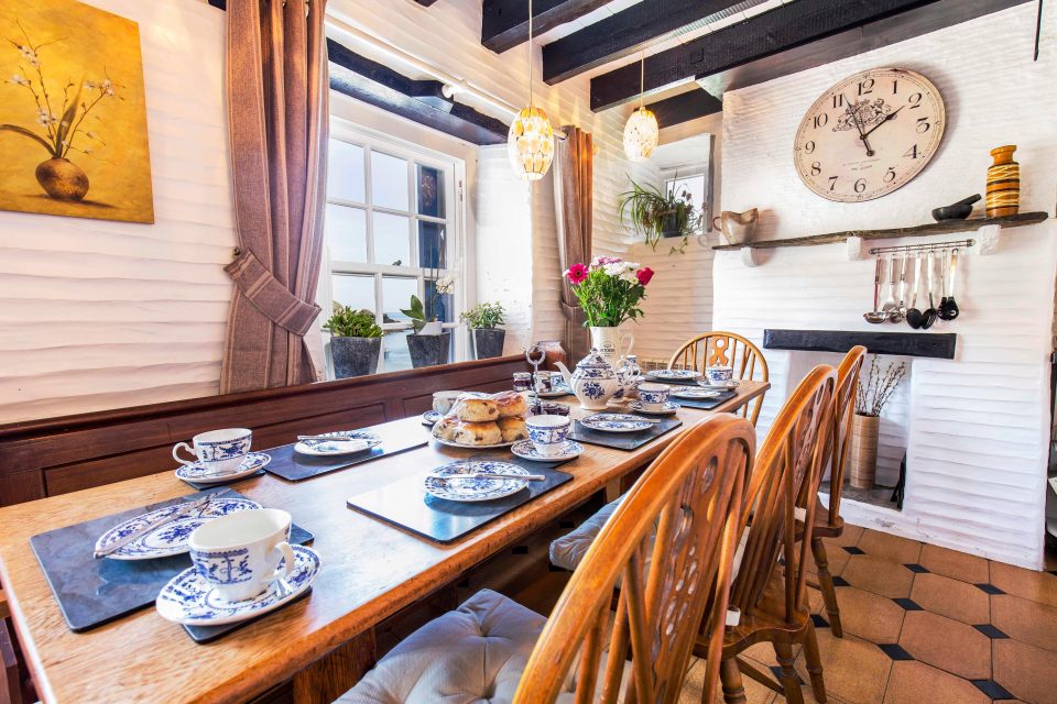  Dinning area in Willy Wilcox Cottage has a white interior with a large clock on the feature wall.