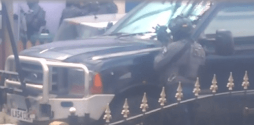  A police officer trains his gun on the house