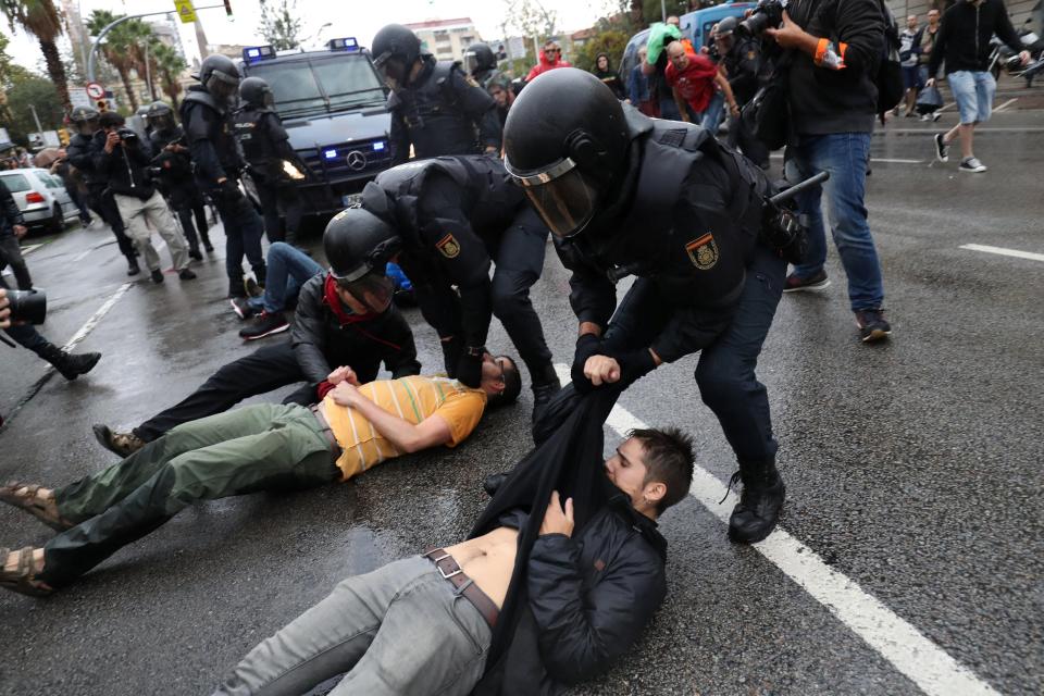  Catalans lie in the street after police raided a polling station in Barcelona