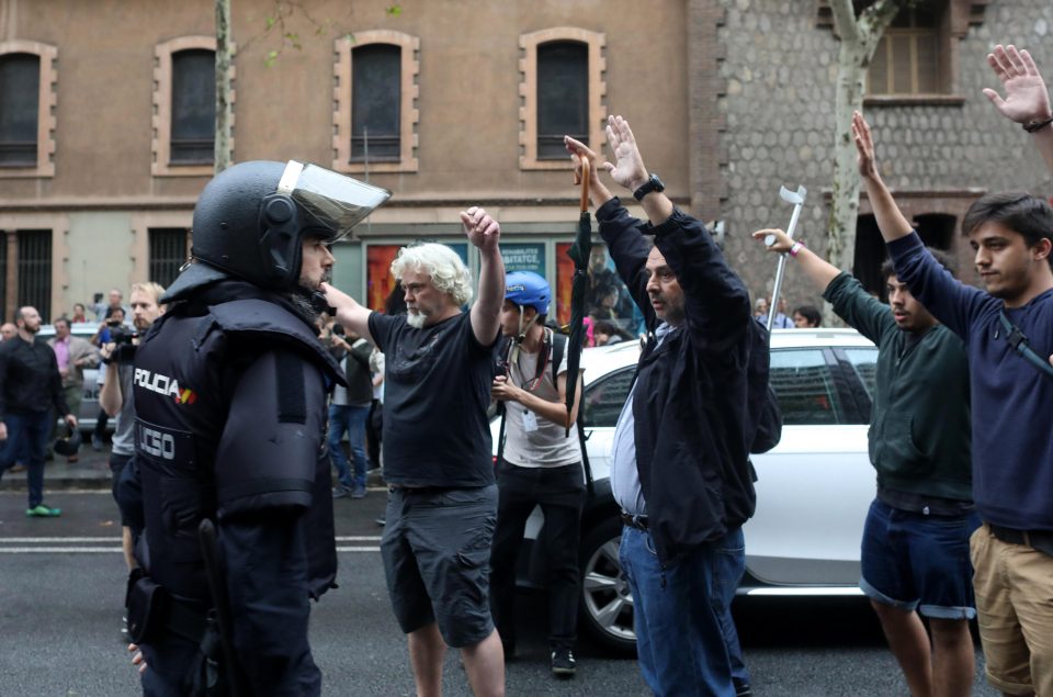  Protesters hold their hands above their heads in front of riot police